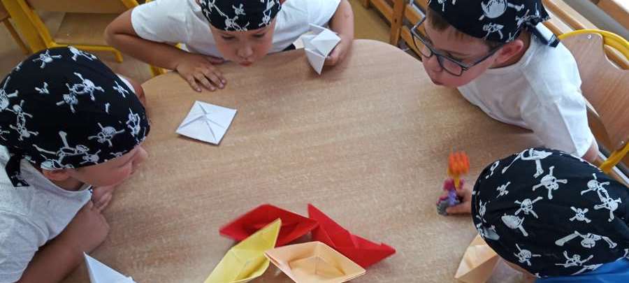 Chłopcy bawią się statkami zrobionymi z papieru