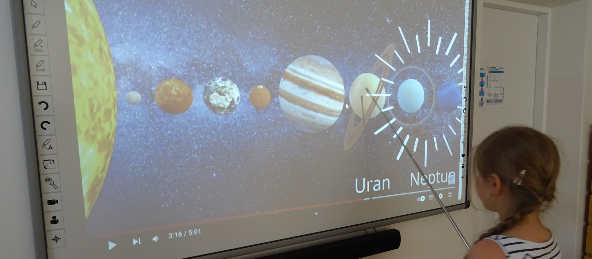 Dziewczynka pokazuje na ekranie planety układu słonecznego