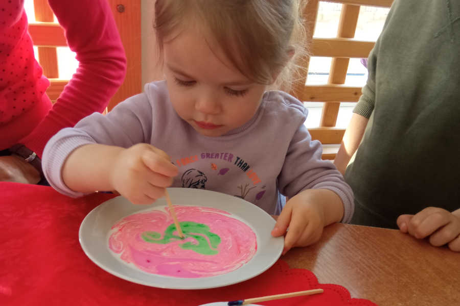 Dziewczynka maluje talerz farbami