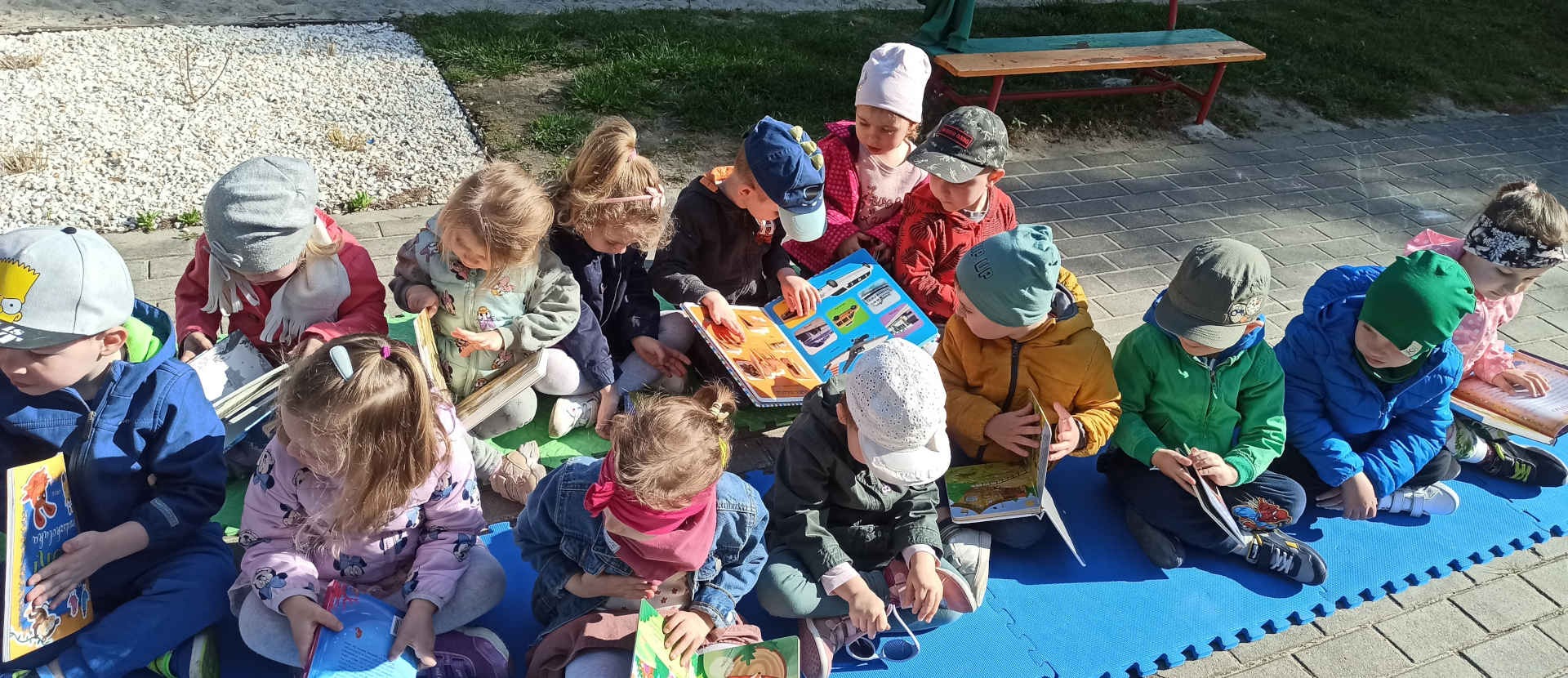 Dzieci w przedszkolnym ogrodzie z książkami