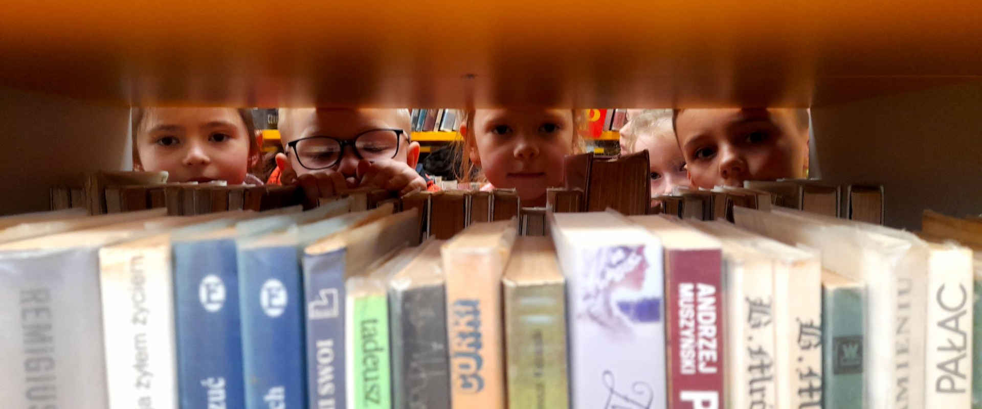 Dzieci w bibliotece zaglądają między książkami