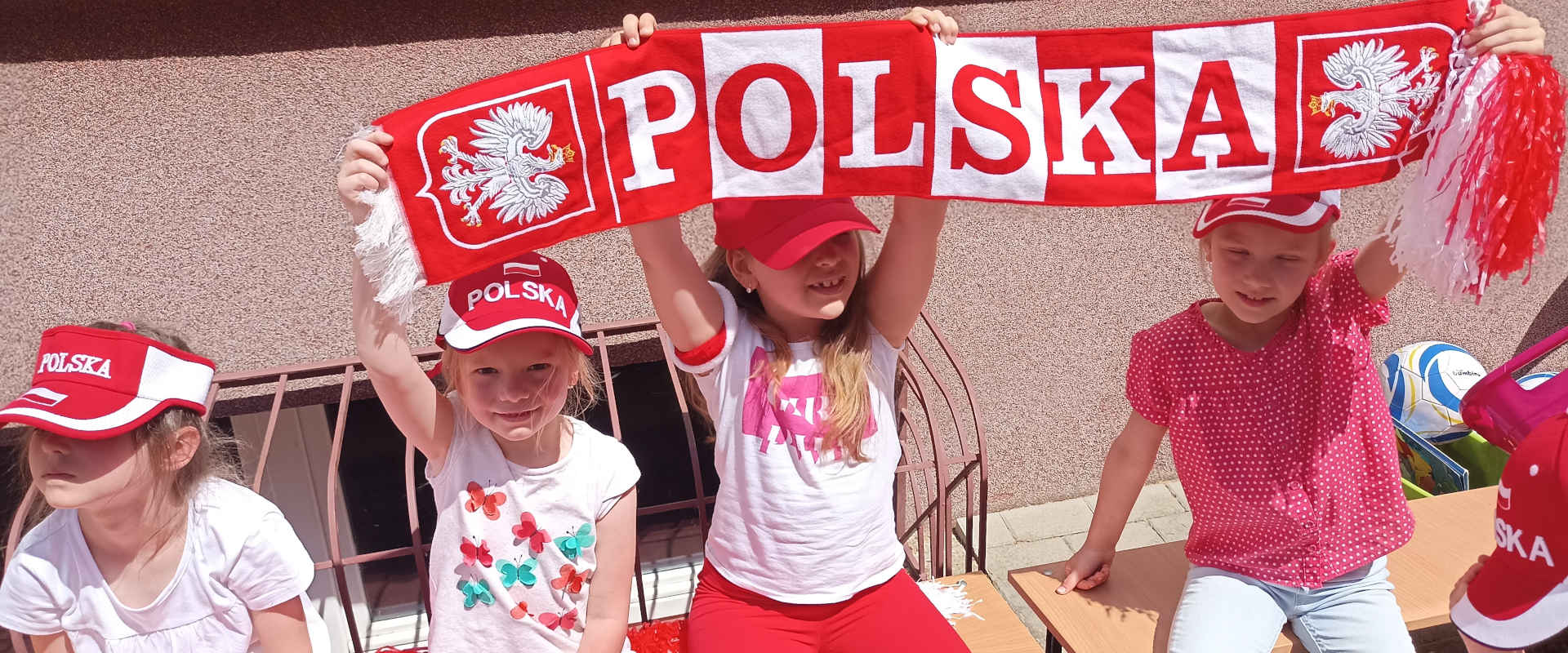 Dzieci z biało czerwonym szalikiem z napisem Polska